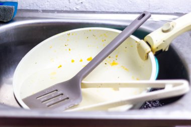 Mutfak kirli bulaşık ve çatal bıçaklarla dolu. Yemek hazırlığından sonra dağınık tabak ve mutfak gereçleriyle dolu metal bir lavabonun içindeki manzara. Temizlik ve hijyen kavramı.