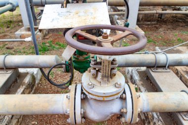 Paslı el tekerleği olan sanayi boru hattı vanası dışarıda yıpranmış altyapı durumunu gösteriyor.