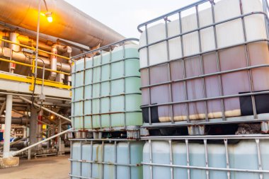 Yığınlanmış orta büyüklükteki konteynırlar endüstriyel tesislerde sıvı depoluyor, ulaşıma hazır..