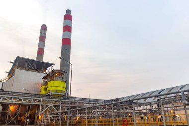 Endüstriyel enerji santrali temiz gökyüzü arka planında bacalarla enerji üretiyor..