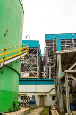 Endüstriyel fabrika karmaşık yapılar, borular, tanklar ve açık hava yolları sergiliyor.