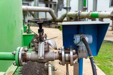 Fabrikada, açık havada, gündüz saatlerinde endüstriyel valf ve mavi kontrol kutusuna yakın çekim..