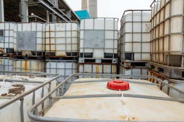 Metal çerçeveli endüstriyel plastik kaplar, sıralı, açık havada, yaşlanmış durumda.