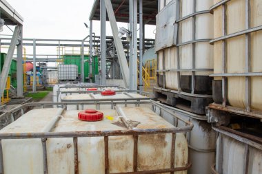 Bir işleme tesisi bahçesinde metal çerçeveler içeren büyük sanayi konteynerleri..