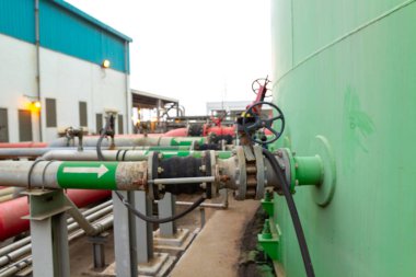 Fabrikadaki sanayi boru hatları ve valf altyapısı, kırmızı, yeşil ve gri.