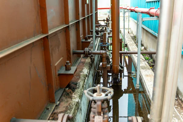 Endüstriyel altyapı karmaşık paslı borular ve yıpranmış metal yapılar gösteriyor.