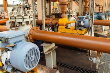 Fabrika ortamında karmaşık endüstriyel boru hattı sistemi ve elektrik motorları, altyapıyı gösteriyor