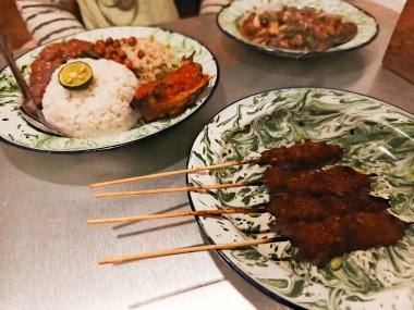 Hindistancevizi sütü ve pandan yaprağıyla pişirilmiş nefis bir Nasi Lemak tabağı ve leziz tavuk şişleri, zengin mutfak mirasını sergiliyor. Süsleme sırasında hizmet
