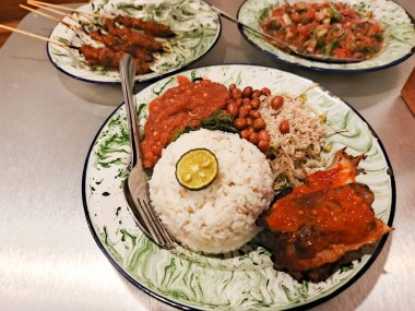 Endonezya mutfağının zengin lezzetlerini geleneksel yemeklerin enfes bir yayılımıyla deneyin. Lezzetli satay, mis kokulu pirinç ve lezzetli sambal sosunun mükemmel kombinasyonunun tadını çıkar. Bir aşçı.