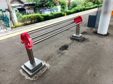 Bu görüntüde bir tren istasyonunda kamu güvenliği engeli var. Metalden inşa edilen ve kırmızı aksanlı boyanmış bariyer, yolcu akışını kontrol etmek ve...