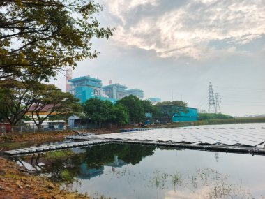 Bu resim, etrafındaki manzarayı yansıtan bir su kütlesi üzerinde yüzen bir güneş paneli kurulumunu gösteriyor. Temiz enerji üretimi, teknolojik yenilikler ve