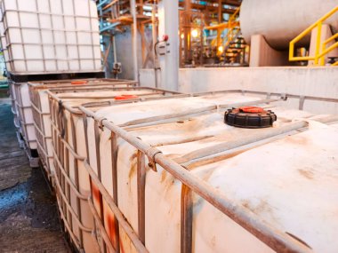 Bir kimya fabrikasında beyaz, küp şeklinde endüstriyel konteynırlar sergileniyor. Üretim tesisinin içindeki çelik iskelet ve depolama işlevlerini vurguluyorlar.