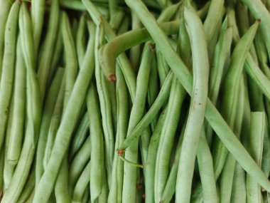 Yakın plan, canlı renklerini ve doğal dokularını sergileyen taze, çiğ yeşil fasulye yığınını yakalar.
