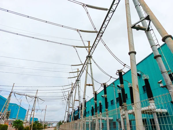 Görüntü, ona bağlı yüksek voltajlı elektrik hatları ve kuleleri olan bir elektrik santrali gösteriyor. Trafo istasyonu sanayi bölgesinde ve yakınındaki binalarda bulunuyor gibi görünüyor. Bu altyapı