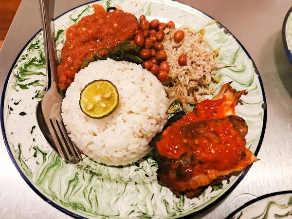 Bir Endonezya karışık pirinç yemeği olan Nasi Campur 'un canlı ve iştah açıcı bir tabağı bir dilim limon dilimli bol miktarda beyaz pirinç ile sunulur. Yanında da tavuk, fıstık ve...