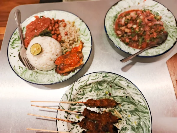Nasi lemak, saate ayam ve sambal matah gibi Endonezya yemekleri vintage tabaklarda servis edildi. Bu resim zengin kültür mirasını ve aşçılık mükemmelliğini yansıtıyor.