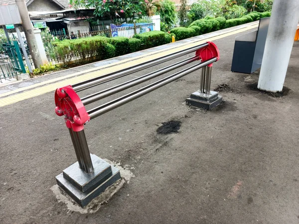 Bu görüntüde bir tren istasyonunda kamu güvenliği engeli var. Metalden inşa edilen ve kırmızı aksanlı boyanmış bariyer, yolcu akışını kontrol etmek ve...