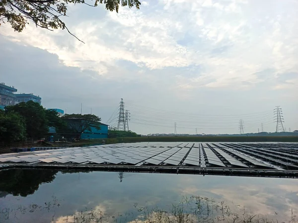 Bu görüntü, yenilenebilir enerji teknolojisinde kayda değer bir gelişme gösteren, yüzen geniş bir güneş paneli çiftliğini yakalıyor. Paneller su yüzeyini zarifçe süslüyor, gökyüzünü yansıtıyor.,
