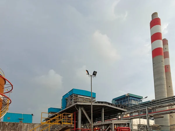 Bu görüntü bulutlu bir günde sanayi altyapısını ve bacalarını vurgulayan bir enerji santralini yakalıyor. Enerji üretimi için gerekli karmaşık mekanizmaları ve yapıları gösteriyor. Şey...