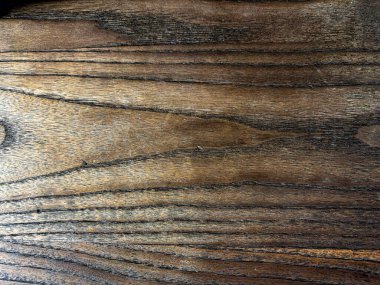 Karmaşık koyu tahtalarını ve pürüzlü yüzeyini gösteren eski kahverengi ahşap bir tahtaya yakın durmak doğal bir arka plan yaratır.