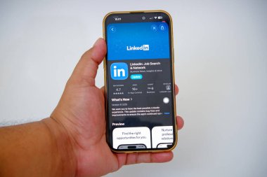 LinkedIn application displayed on a smartphone screen held by a person showing details for job search and professional networking update in a mobile app store highlighting its features and user ratings