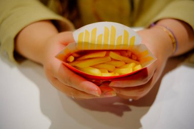 Bir insanın ellerinin açık bir karton patates kızartmasını yemeğe hazır halde tutuşu. Fast food atıştırması.