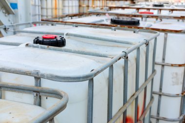 Metal kafeslere sahip orta büyüklükteki sanayi konteynırları açık havada depolanmıştır. Bu IBC 'ler nakliye ve kimyasal taşımacılıkta ağır kullanımdan kaynaklanan pas ve kir belirtileri göstermektedir.