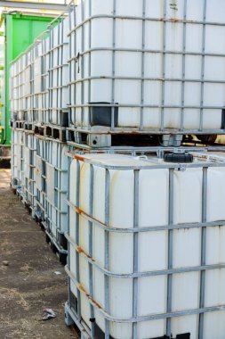 Endüstriyel sıvı depolama ve taşımacılık için kullanılan metal kafesli sayısız beyaz plastik Toplu Konteynır (IBC) dışarıda istiflenmiştir..