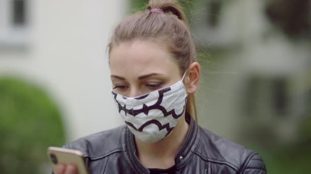 Mujer joven con una máscara está teniendo una conversación por teléfono. — Vídeos de Stock
