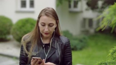 Genç ve mutlu kadın bahçede müzik dinliyor, şarkı söylüyor ve dans ediyor..