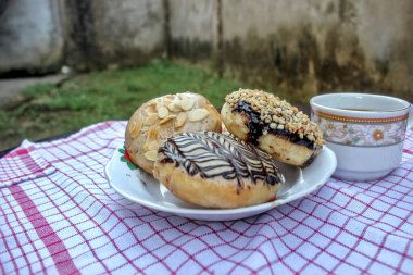 A delicious breakfast donuts and coffee arranged on a checkered tablecloth, a food photography concept.