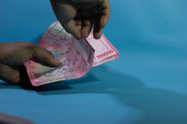 Bir el resmi yığından bir banknot alıyor, vergilendirmeyi, mali kesintiyi ve ekonomik sorumluluğu simgeliyor..