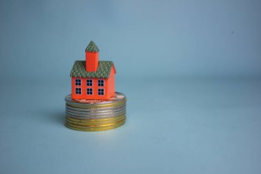 Birikimleri, yatırımları ve emlak büyümesini sembolize eden temiz boşluklu bozuk paraların üzerine yerleştirilmiş küçük bir ev..