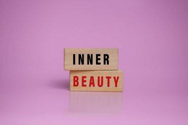 Ahşap bloklardaki iç güzellik kelimeleri pembe arka planda izole edilmiş.