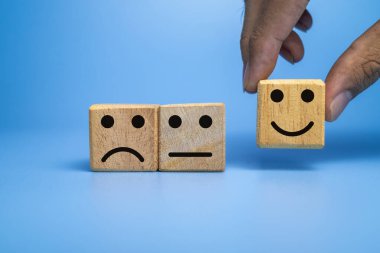 mavi arkaplanda izole edilmiş tahta küplerde hüzünlü, düz ve mutlu yüz ifadesi.