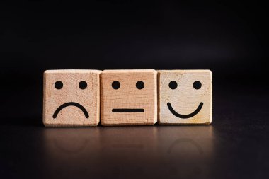 Kara arka planda izole edilmiş tahta küplerdeki hüzünlü, düz ve mutlu yüz ifadesi.