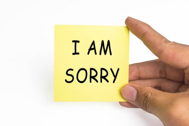 Erkek eli yapışkan notlar tutuyor. Beyaz arka planda özür dilerim.