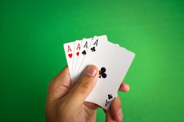 Yetişkinlerin elinde dört as, yeşil masada arka plan için poker kartları var.
