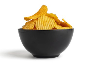 Beyaz arka planda izole edilmiş siyah kasede sarı patates cipsi.