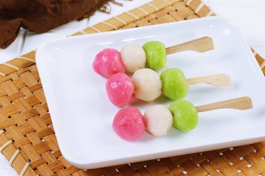 Sanshoku Dango pembe, beyaz ve yeşil pirinçli hamur tatlısı içeren beyaz bir tabakta düzenlendi..