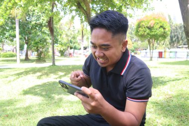 Genç adam parkta telefonuna bakarken öfkeyle tepki veriyor..