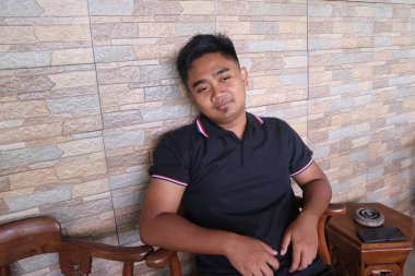 Genç adam oturuyor ve bir sandalyede dinleniyor..