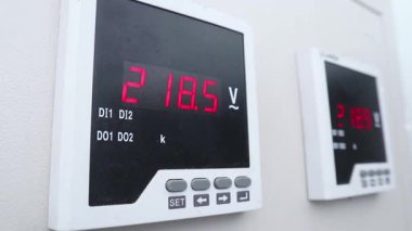 Modern bir dijital voltaj ölçer üzerinde gösterilen hassas elektrik ölçümleri, endüstriyel kontrol paneli içindeki kritik güç ölçümlerini gösteriyor