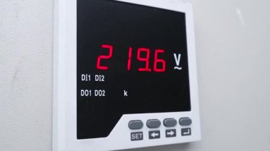 Modern bir dijital voltaj ölçer üzerinde gösterilen hassas elektrik ölçümleri, endüstriyel kontrol paneli içindeki kritik güç ölçümlerini gösteriyor