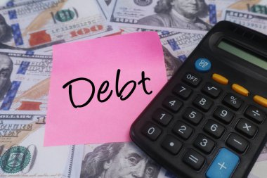 Ekonomik zorlukları ve bütçeyi sembolize eden, dolar ve hesap makineli borç konsepti.