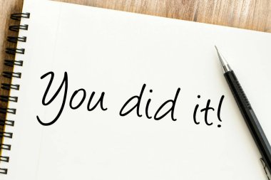 El yazısıyla yazılmış ilham verici sözler. Bir defter sayfasında, bir kalemin yanında, başarıyı, başarıyı ve bir amaca ulaşmanın sevincini kutluyorsun.