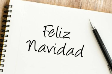 Zarif bir şekilde el yazısıyla yazılmış Mutlu Noeller notu, yanında parlak bir kalem, sıcak tatil dileklerini simgeliyor.