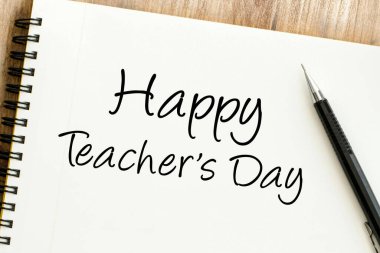 Mutlu Öğretmenler Günü mesajı bir kalemle birlikte spiral bir deftere yazılmış eğitimcileri ve paha biçilmez katkılarını kutluyor.