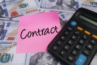Sözleşme metni, hesap makinesi ve Amerikan dolarları içeren pembe yapışkan bir not. Yasal anlaşma ve iş kavramı.