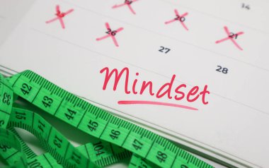 Ölçüm bandıyla takvimdeki zihniyet metni. Ruh sağlığı kavramı, fitness hedefleri ve yaşam motivasyonu.